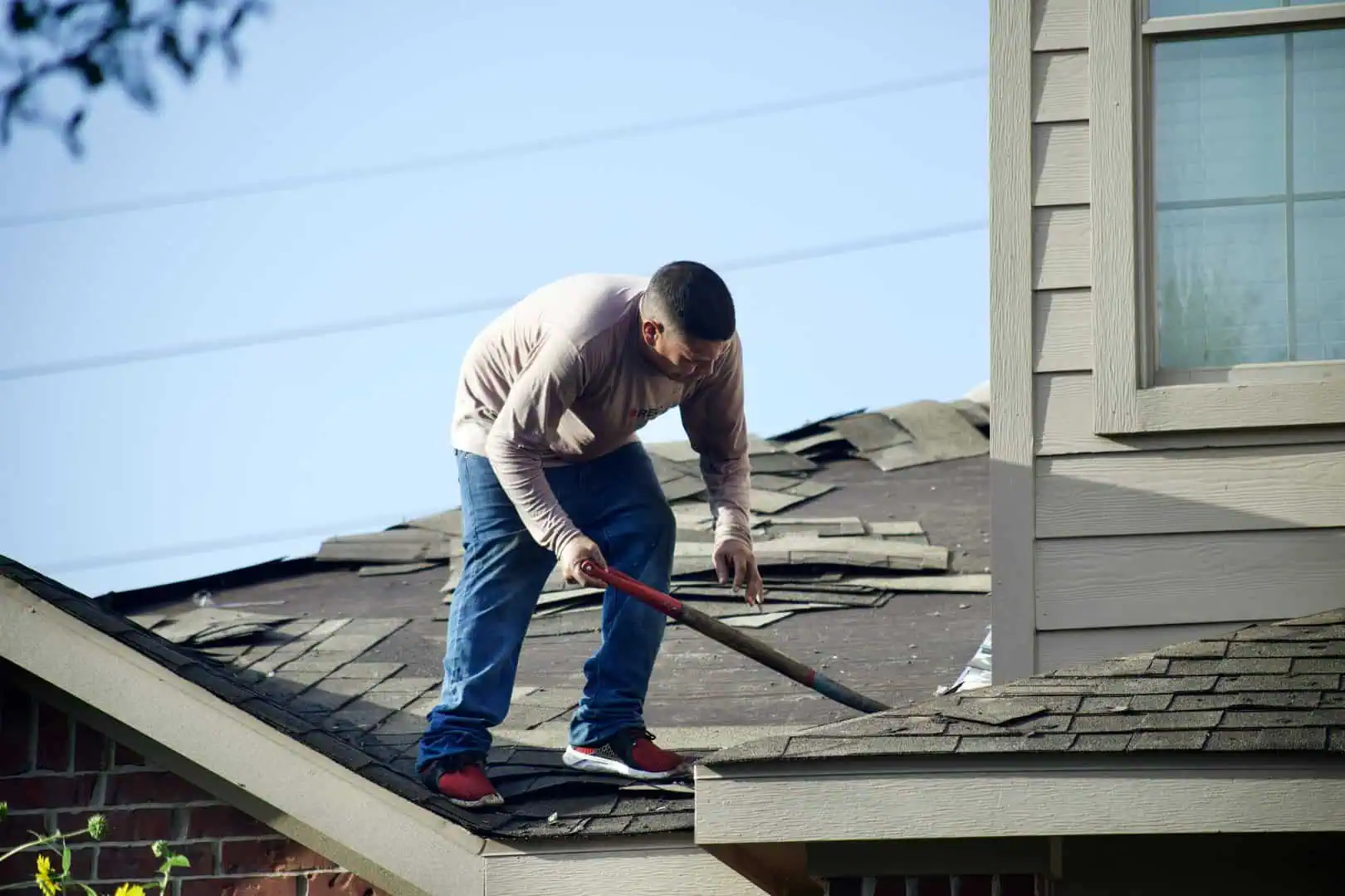 Man using roof ripper to remove shingles from roof